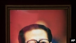 一位婦女走過江澤民畫像.當局否認江已經去世。