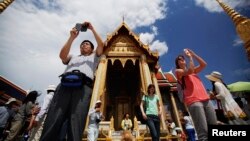 Tourists take pictures as they visit the Grand Palace in Bangkok. 