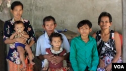 កុមារា ក្រន និលមុនី ជាមួយ​ជីតា គឺ​លោក សួន ក្រិ អាយុ​៦១ឆ្នាំ និង​ក្រុមគ្រួសារ​ដែល​រស់នៅ​ជាមួយគ្នា​ ថត​រូបជុំគ្នា​នៅ​ផ្ទះ ស្ថិត​ក្នុង​ស្រុក​បន្ទាយស្រី ខេត្តសៀមរាប កាល​ពីថ្ងៃ​ទី​១៣ ខែកក្កដា ឆ្នាំ២០១៧។ (ស៊ុន ណារិន/VOA)