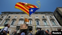 FILE - A man waves an "Estelada," Catalan separatist flag, outside the Generalitat Palace in Barcelona, Spain, May 17, 2018. 