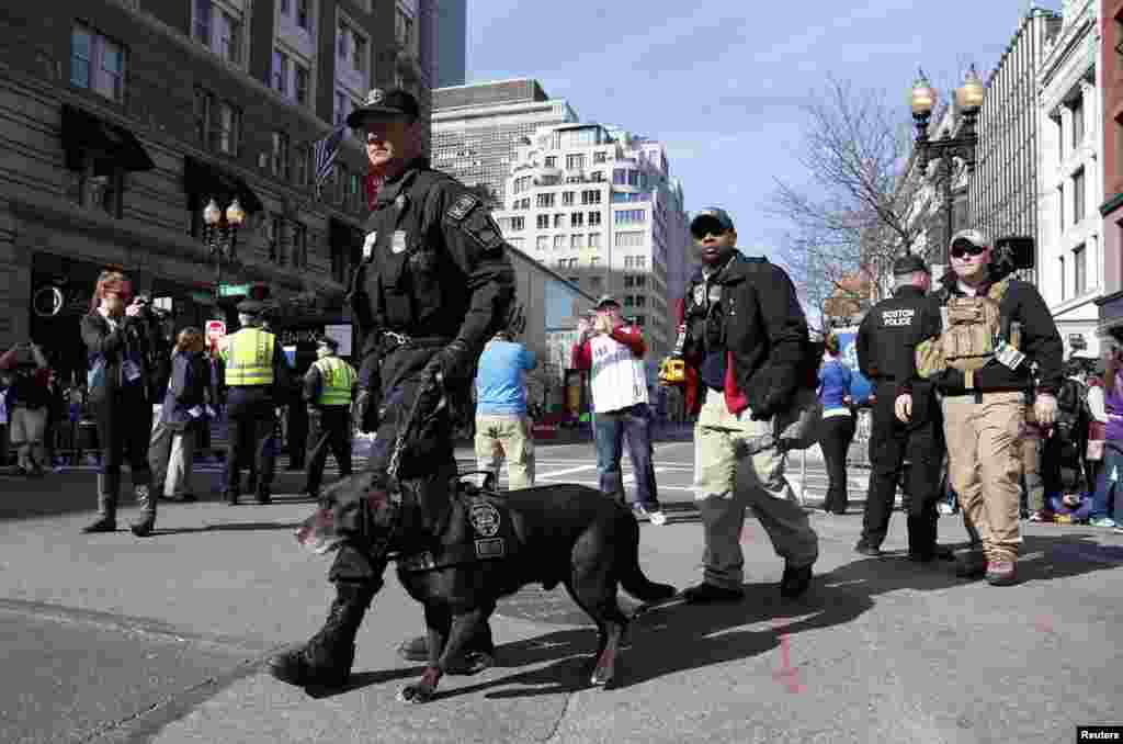 Boston police officers, part of the K-9 unit, patrol Boylston Street near the finish line before the start of the 2014 Boston Marathon, Boston, Mass., April 21, 2014.