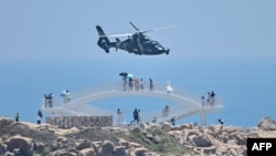 中国福建省平潭岛上的游客在观看中国军队在台湾附近举行的实弹军演。（2022年8月4日）