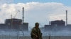 FILE - A serviceman with a Russian flag on his uniform stands guard near the Zaporizhzhia nuclear power plant outside the Russian-controlled city of Enerhodar, in the Zaporizhzhia region, Ukraine, Aug. 4, 2022. 