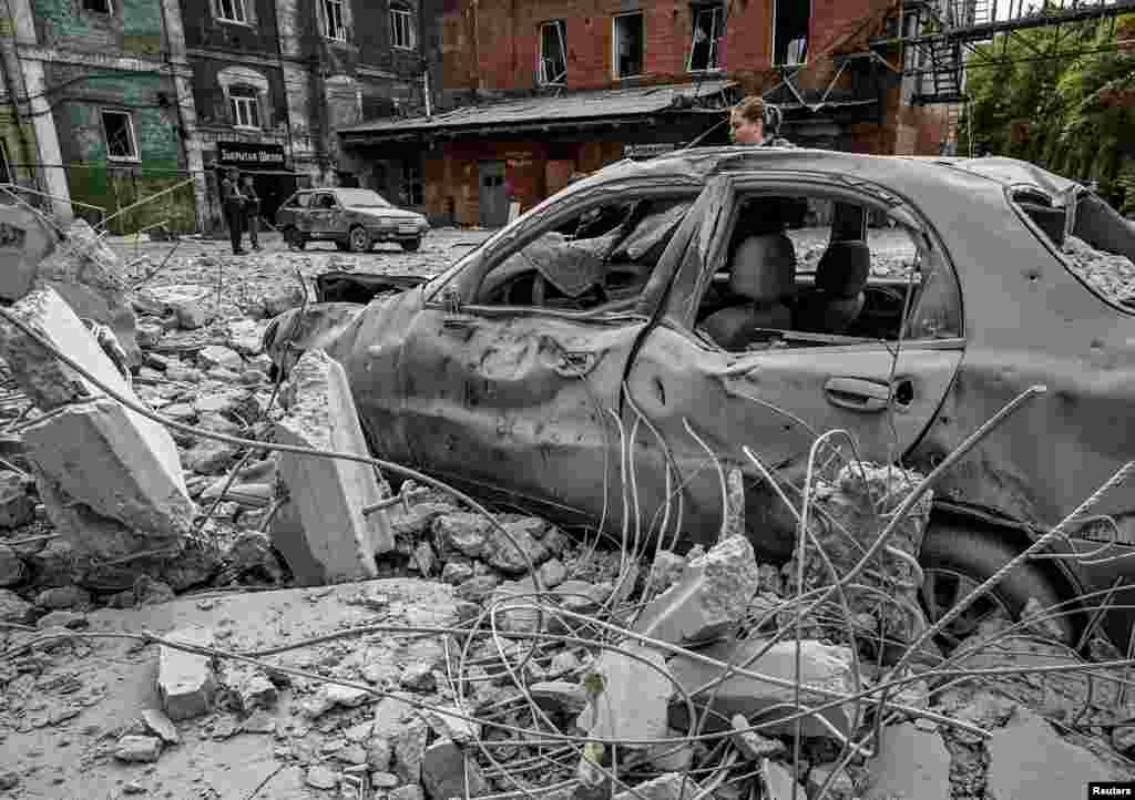 A woman stands by her destroyed car near an old mill, built around 1885, also destroyed during a Russian missile attack in Zaporizhzhia, Ukraine.