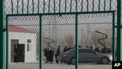 FILE - Residents line up inside the Artux City Vocational Skills Education Training Service Center, which was revealed by leaked documents to be a forced indoctrination camp at the Kunshan Industrial Park in Artux in western China's Xinjiang region, Dec. 3, 2018.