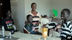 Achut Deng poses for a photo at her home in Sioux Falls, South Dakota, Sept. 17, 2022, with her sons, from left, Deng Kuek, Kuek Kuek and Mayom Meyon. 