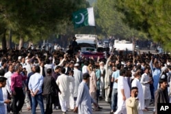People walk with an ambulance carrying the casket of slain senior Pakistani journalist Arshad Sharif after his funeral prayer, in Islamabad, Oct. 27, 2022.