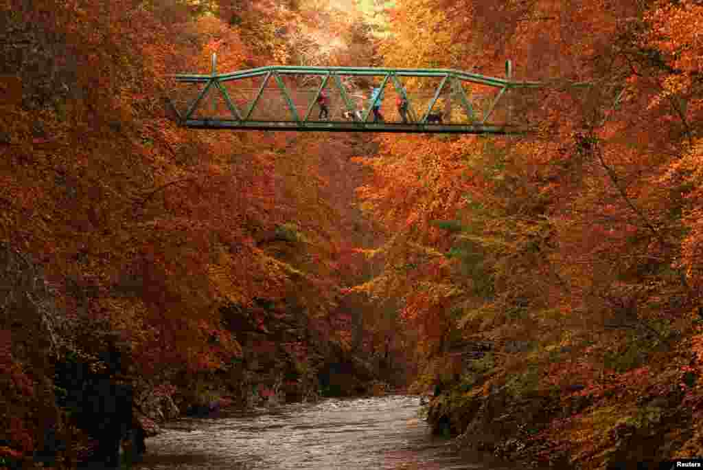 People cross a foot bridge over the River Garry near Pitlochry, Scotland, Britain, Oct, 26, 2022. 