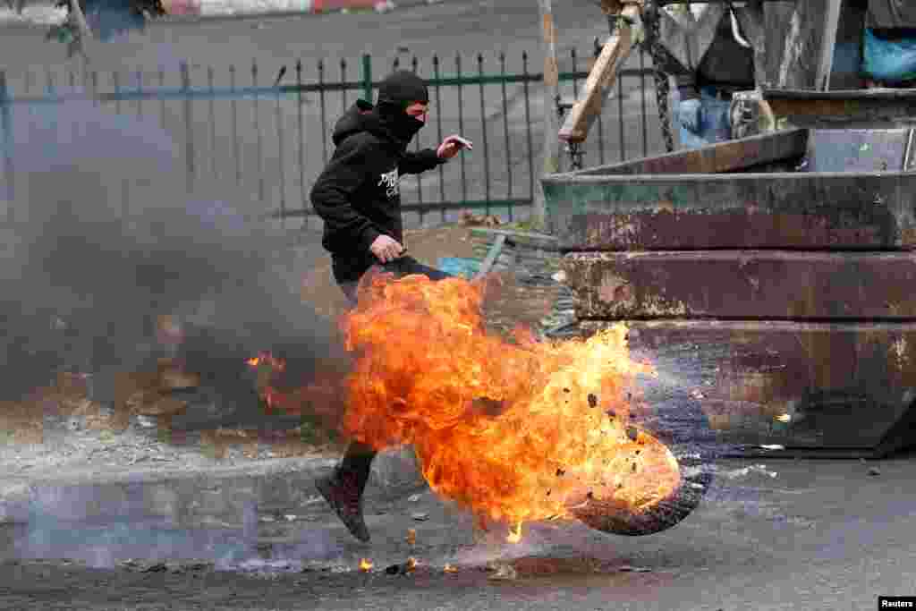 A man kicks a burning tire, as Palestinians clash with Israeli forces during a protest in Hebron, in the Israeli-occupied West Bank.