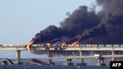 Black smoke billows from a fire on the Kerch bridge that links Crimea to Russia, after a truck exploded, near Kerch, Oct. 8, 2022.