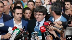 Catalan President Carles Puigdemont, center, speaks to the media at a sports arena designated a polling station by the Catalan government, in Sant Julia de Ramis, near Girona, Spain, Oct. 1, 2017.