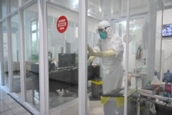 Seorang dokter spesialis paru-paru (kanan) di dalam zona kuning memakai alat pelindung diri (APD), dan seorang perawat (kiri) tengah bekerja di zona hijau di rumah sakit khusus penanganan pasien COVID-19 di Bogor, 9 Februari 2021.