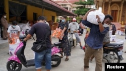 FILE PHOTO - People carry sacks of rice and other food donated by the local government inside a red zone with strict lockdown measures during the latest outbreak of the coronavirus disease (COVID-19) in Phnom Penh, Cambodia, April 30, 2021. REUTERS/Cindy Liu