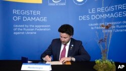 Crnogorski premijer Dritan Abazović potpisuje Deklaraciju o podršci proširenom djelimičnom sporazumu o registru štete na samitu Savjeta Evrope u Islandu (Foto: AP/Alastair Grant)