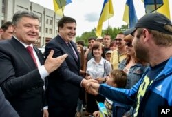 FILE - Seen during better times, Ukrainian President Petro Poroshenko, left, and then newly-appointed Odesa region governor Mikheil Saakashvili, second left, shake hands with local residents, in Odesa, Ukraine, May 30, 2015.
