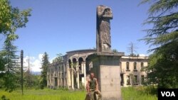 რუსი ოკუპანტი ოკუპირებულ გალში, შოთა რუსთაველის განადგურებული ძეგლის ფონზე