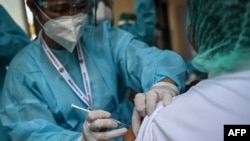 ရန်ကုန်မြို့ရှိ ဧရာဝတီကိုဗစ်စင်တာမှာ ကိုဗစ်ကာကွယ်ဆေး ထိုးခံနေတဲ့ ကျန်းမာရေးဝန်ထမ်းတဦး။ (ဇန်နဝါရီ ၂၇၊ ၂၀၂၁)