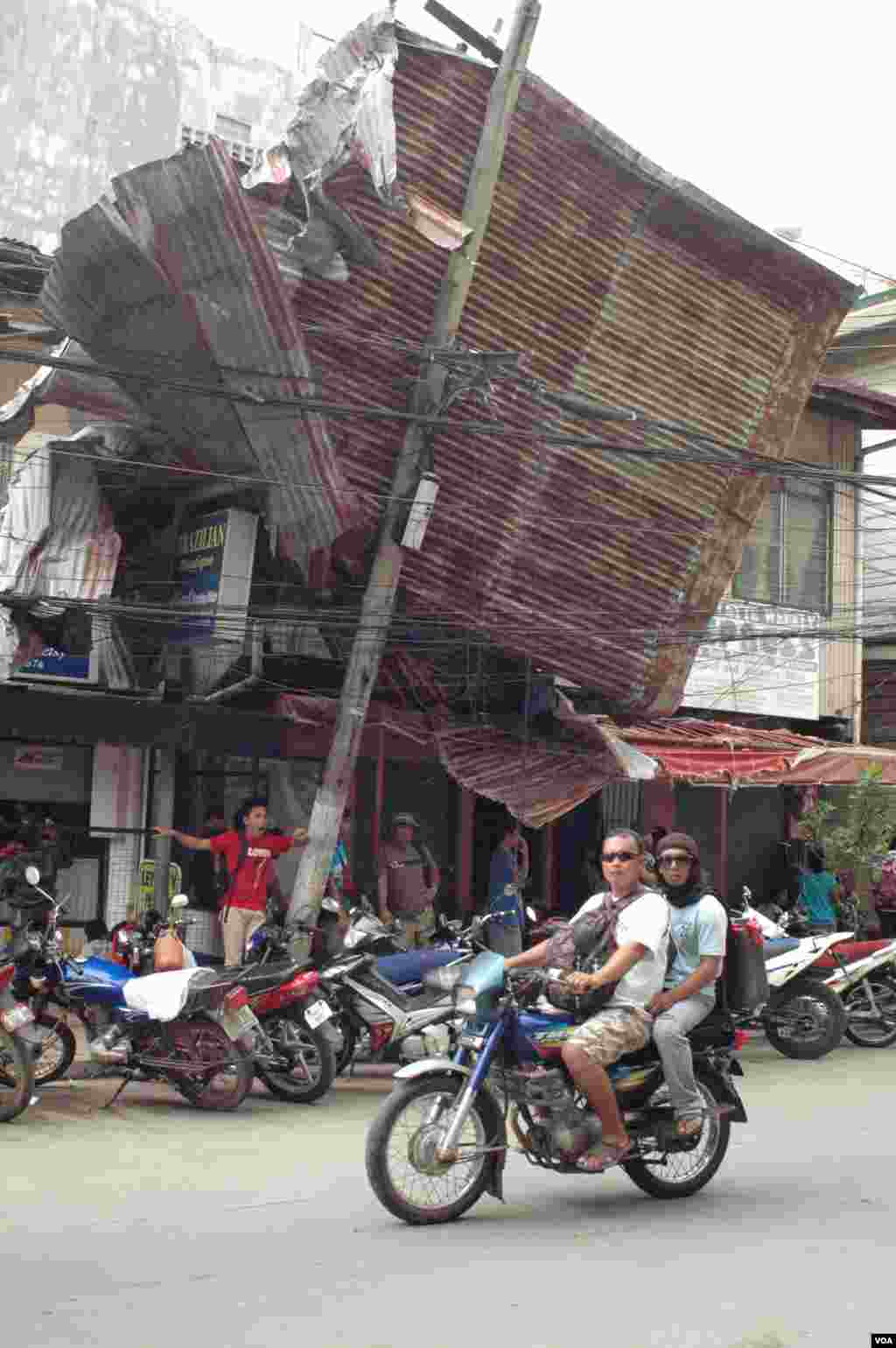 A motorcyclist rides past a damaged store in Ormoc, Philippines, Nov. 17, 2013. (Steve Herman/VOA)