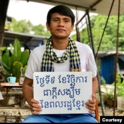 លោក ឈុន វាន សកម្មជន​គណបក្ស​សង្រ្គោះ​ជាតិ ដែល​ត្រូវ​បាន​តាម​ចាប់​ខ្លួន កាន់បដា​ដែល​សរសេរ​ថា «ថ្ងៃទី៩ វិច្ឆិកា ជាក្តីសង្ឃឹម​របស់​ពលរដ្ឋ​ខ្មែរ»។