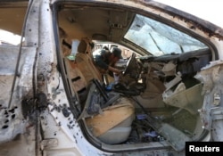 An Afghan security forces member inspects a vehicle at the site of a suicide attack in Jalalabad, Afghanistan, March 7, 2018.
