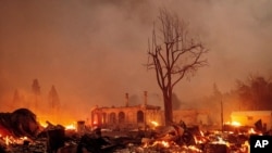 Buildings burn as the Dixie Fire tears through the Greenville community of Plumas County, Calif., on Aug. 4, 2021.