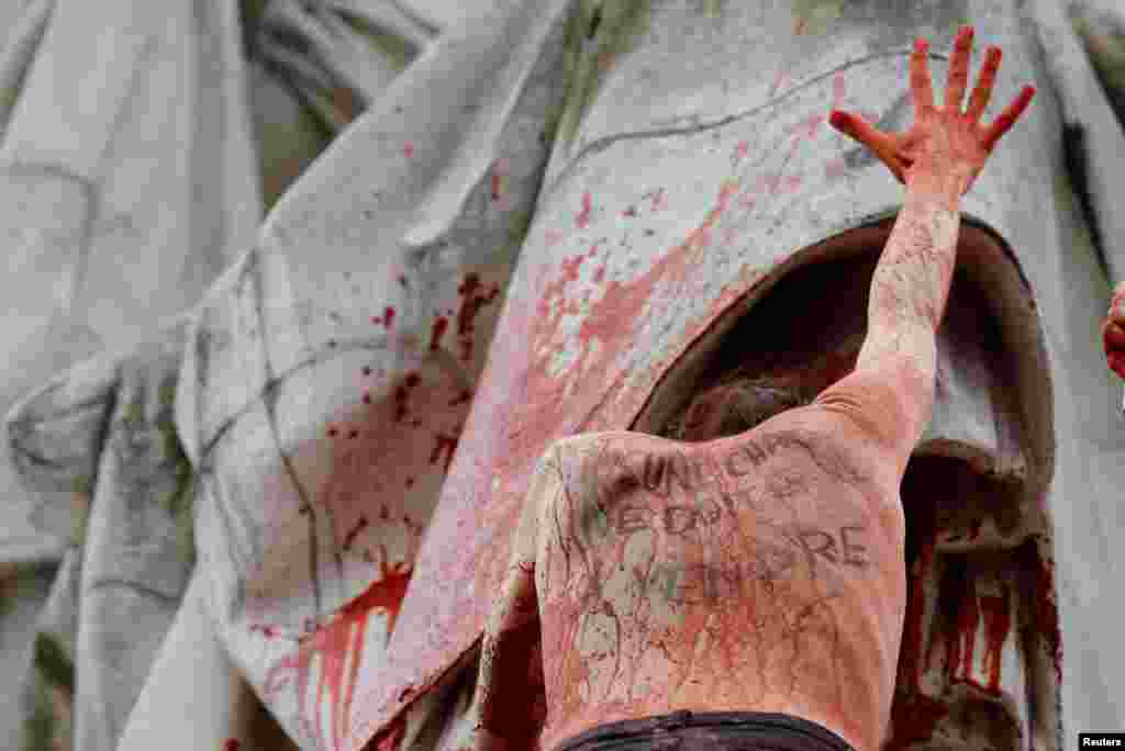 A woman with the message written on her back, "No flesh should be for sale" stands on the statue at the Place de la Republique during a protest to highlight the pay disparity between women and men, in Paris, France, March 8, 2019.