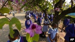 Schoolchildren wait to enter their school in Harare, Zimbabwe, Monday Sept, 28, 2020. Zimbabwe schools have reopened in phases, but with smaller number of pupils, more teachers and other related measures to enable children to resume their education withou
