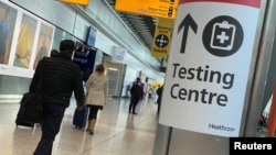 Travellers pass a sign for a COVID-19 test centre at Heathrow Airport, London, Britain, February 13, 2021. 