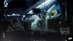 Australian passengers disembarked from the quarantined Diamond Princess cruise ship, wave from the bus as they leave a port Wednesday, Feb. 19, 2020, in Yokohama, near Tokyo.