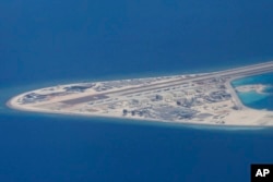 FILE - In this April 21, 2017, photo, an airstrip and buildings on China's man-made Subi Reef in the Spratly chain of islands in the South China Sea are seen from a Philippine Air Force C-130.