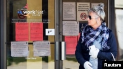 A woman looks to get information about job application in front of IDES (Illinois Department of Employment Security) WorkNet center in Arlington Heights, Ill., Thursday, April 9, 2020. 
