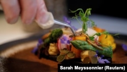 French chef Laurent Veyet puts a cricket on a dish in his restaurant Inoveat serving insect-based food in Paris, France, May 12, 2021. (REUTERS/Sarah Meyssonnier)
