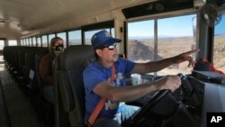 FILE - School bus driver by Kelly Maestas travels along a dirt road, with social worker Victoria Dominguez, outside Cuba, N.M., Oct. 19, 2020. The switch to remote learning in rural New Mexico has left some students profoundly isolated.