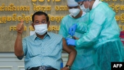 រូបឯកសារ៖ លោកនាយករដ្ឋមន្ត្រី ហ៊ុន សែន លើកមេដៃបង្ហាញអ្នកសារព័ត៌មាន ខណៈលោកទទួលចាក់វ៉ាក់សាំងបង្ការជំងឺកូវីដ១៩ របស់ក្រុមហ៊ុន AstraZeneca នៅមន្ទីរពេទ្យកាល់ម៉ែត្រ រាជធានីភ្នំពេញ ថ្ងៃទី៤ ខែមីនា ឆ្នាំ២០២១។