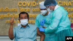 Cambodian Prime Minister Hun Sen gestures as he receives the AstraZeneca vaccine during a vaccination campaign against the Covid-19 coronavirus at Calmette hospital in Phnom Penh, Cambodia, on March 4, 2021. (Photo by Kok Ky / AFP) 