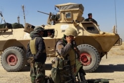 Afghan security forces stand near an armored vehicle during ongoing fighting between Afghan security forces and Taliban fighters in the Busharan area on the outskirts of Lashkar Gah, the capital city of Helmand province, May 5, 2021.