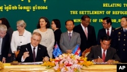 FILE - Australian Immigration Minister Scott Morrison, front left, signs a document together with Cambodian Interior Minister Sar Kheng, front right, during a signing ceremony of a controversial deal on resettlement of refugees inside the Interior Ministry in Phnom Penh, Cambodia, Friday, Sept. 26, 2014. 