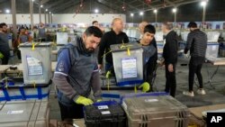 دیمەنی چەند کارمەندێکی کۆمسیۆنی هەڵبژاردنەکانی عێراق لە کاتی کۆکردنەوەی چەند سندوقێکی دەنگدان لە شاری بەغدا لە ڕۆژی 21-12-2023.