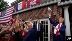 El expresidente Donald Trump lanza una pelota de fútbol americano a la multitud durante una visita a Alpha Gamma Rho, en la Universidad Estatal de Iowa antes de un partido de fútbol americano universitario el 9 de septiembre de 2023, en Ames, Iowa. (Foto AP/Charlie Neibergall)