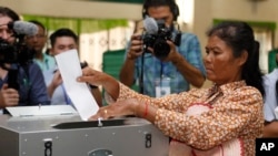 ស្ត្រីម្នាក់​ដាក់​សន្លឹកឆ្នោត​ខ្លួន​ចូល​ក្នុង​ហឹបឆ្នោត​នៅការិយាល័យ​បោះឆ្នោត​តាខ្មៅ​ខេត្ត​កណ្តាលប្រទេស​កម្ពុជា​កាលពីថ្ងៃទី២៩ កក្កដា ឆ្នាំ២០១៨។