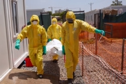 FILE - Members of medical team carry the body of a deceased COVID patient on a stretcher at a Ministry of Health Infectious Disease Unit in Juba, South Sudan, May 28, 2020.