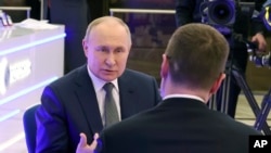 Presiden Rusia Vladimir Putin (kiri) berbicara dengan koresponden stasiun televisi pemerintah Rusia, Rossiya, Pavel Zarubin di Moskow, pada 14 Februari 2024. (Foto: Alexander Kazakov, Sputnik, Kremlin Pool Photo via AP)