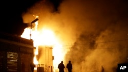 People walk away from a storage facility on fire after the announcement of the grand jury decision Monday, Ferguson, Missouri, Nov. 24, 2014.