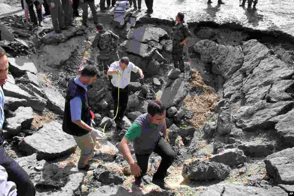 Syrian inspectors investigate the crater in front of a damaged military intelligence building where two bombs exploded in Damascus, Syria, May 10, 2012.