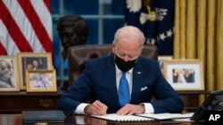 FILE - President Joe Biden signs an executive order, in the Oval Office of the White House, in Washington, Feb. 2, 2021.
