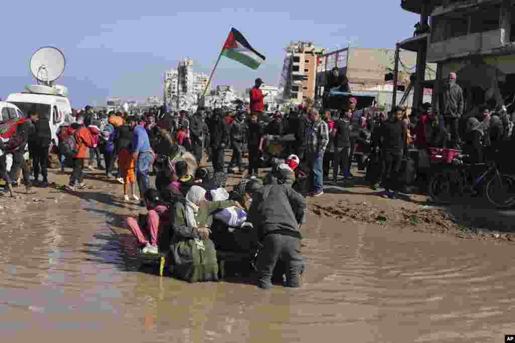 A family on a horse-drawn cart struggles to cross a puddle of water as displaced Palestinians return to their homes in the northern Gaza Strip.