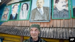 У російському селі поблизу Москви художник Михайло Коргунов перед своїми картинами - портретами прем’єр-міністра Росії Медведєва, російського царя Петра, Володимира Леніна та Йосипа Сталіна. Фото: AP/Pavel Golovkin