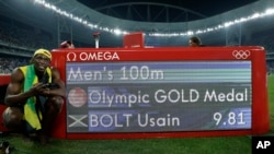 Usain Bolt pose devant son temps de course pour les 100 m après avoir gagné la finale, à Rio de Janeiro, le 14 août 2016.