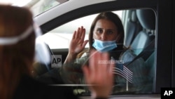 FILE - U.S. District Judge Laurie Michelson, left, administers the Oath of Citizenship to Hala Baqtar during a drive-thru naturalization service in Detroit.