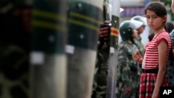 2009年7月9日一维吾尔族女孩在新疆省乌鲁木齐观看游行被防暴警察拦住。